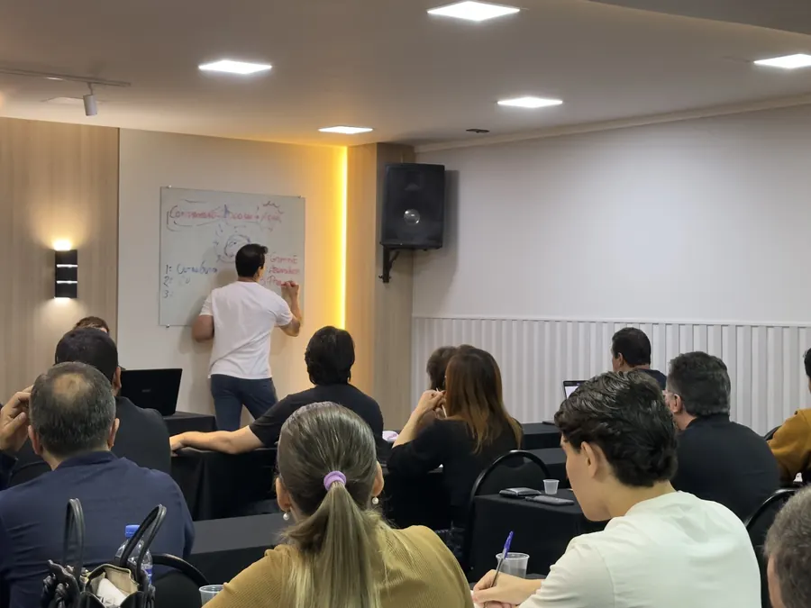 Mentor explicando conceitos no quadro branco durante o encontro mensal