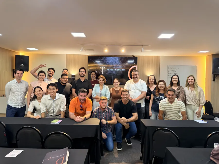Turma do encontro mensal Perpetuadores reunida em frente ao telão com a marca Perpetuadores